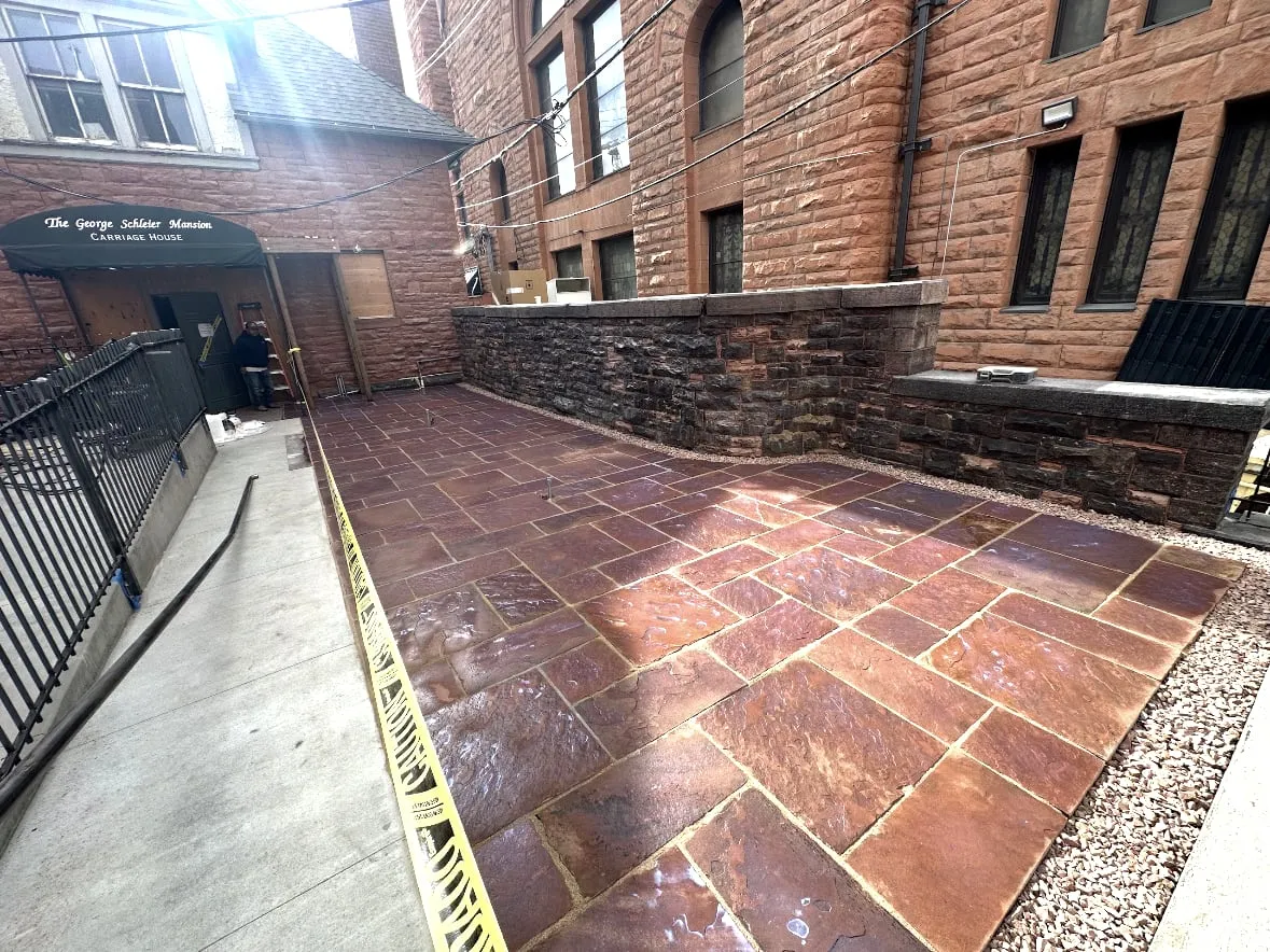 Herringbone-laid stone patio beside a historic brick building