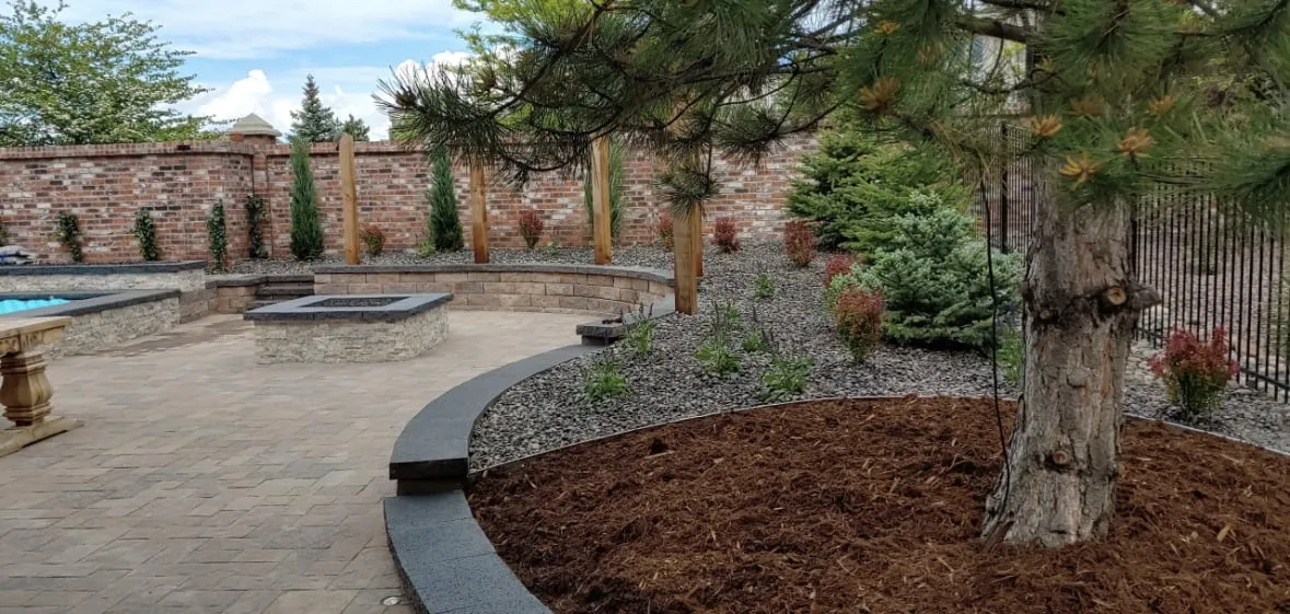 Paver patio with a fire feature and a mulched tree bed