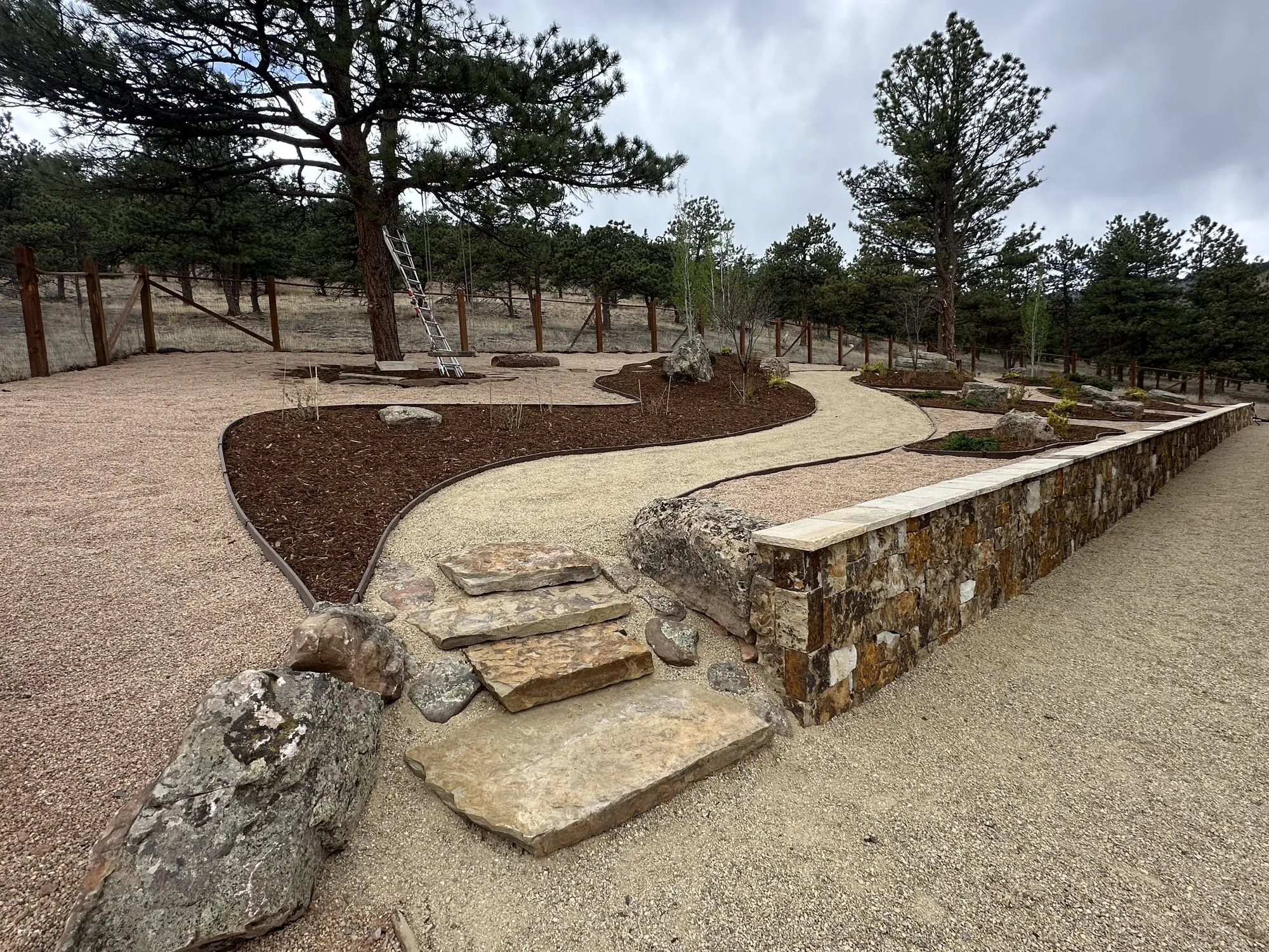 Boulder retaining wall with flagstone and native plants